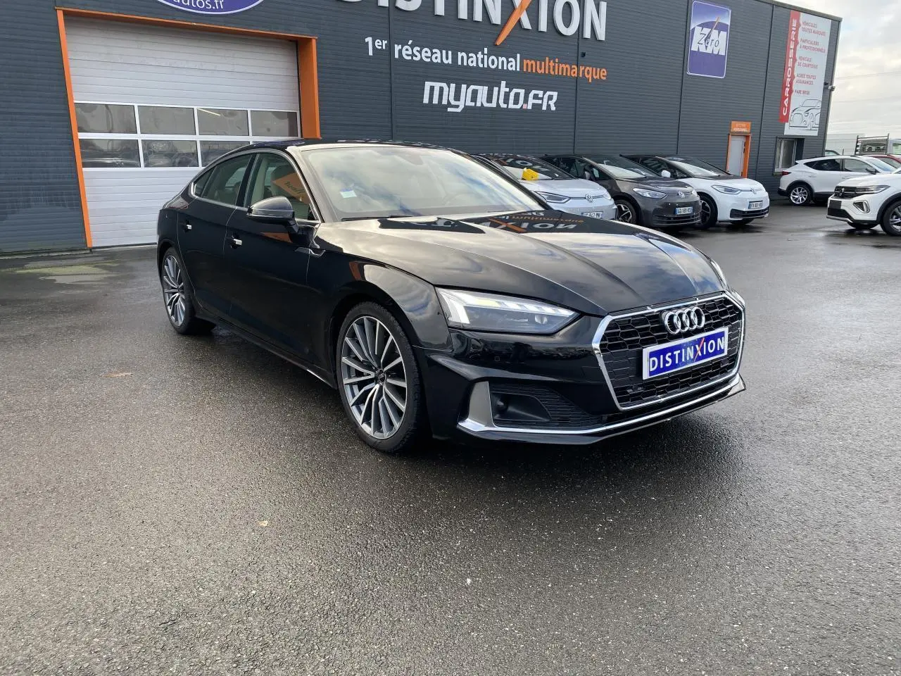 Audi A5 Sportback noir mythic métallisé vue 3/4 avant droit avec jantes multibranches grises contrastées.