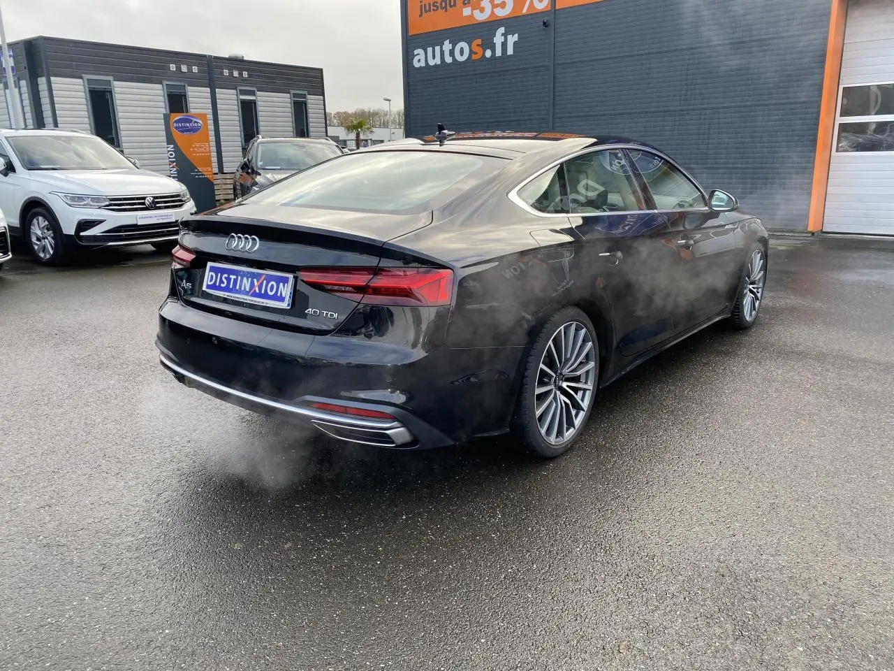 Audi A5 Sportback noir mythic métallisé vue 3/4 arrière droit avec jantes multibranches et échappement visible