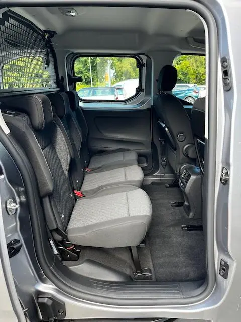 Vue intérieure côté droit du Peugeot Rifter gris foncé 2024, montrant les sièges arrière et la séparation grillagée avec le coffre.