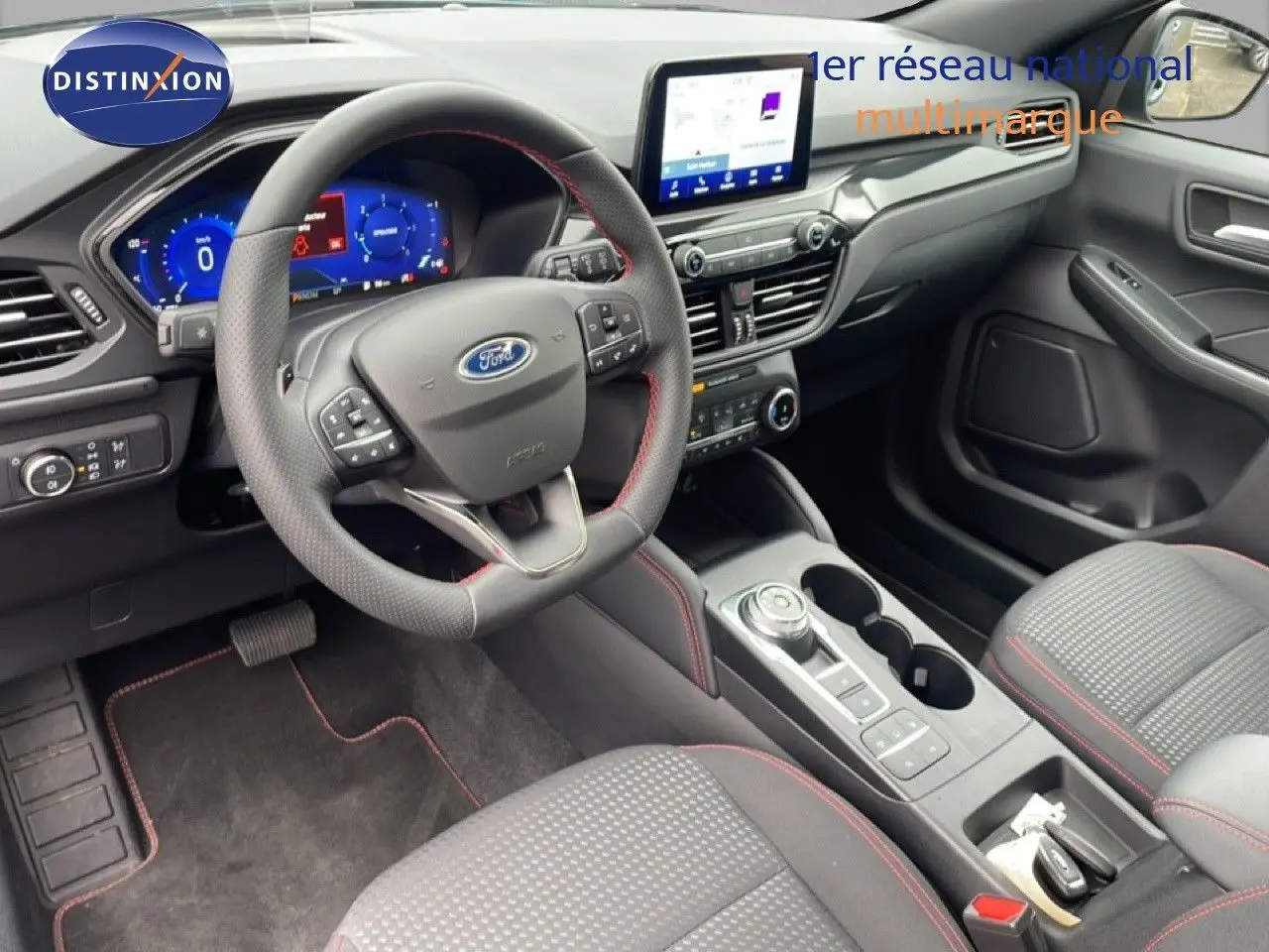 Vue intérieure côté conducteur du Ford Kuga 2024, volant cuir noir avec surpiqûres rouges et écran tactile central.