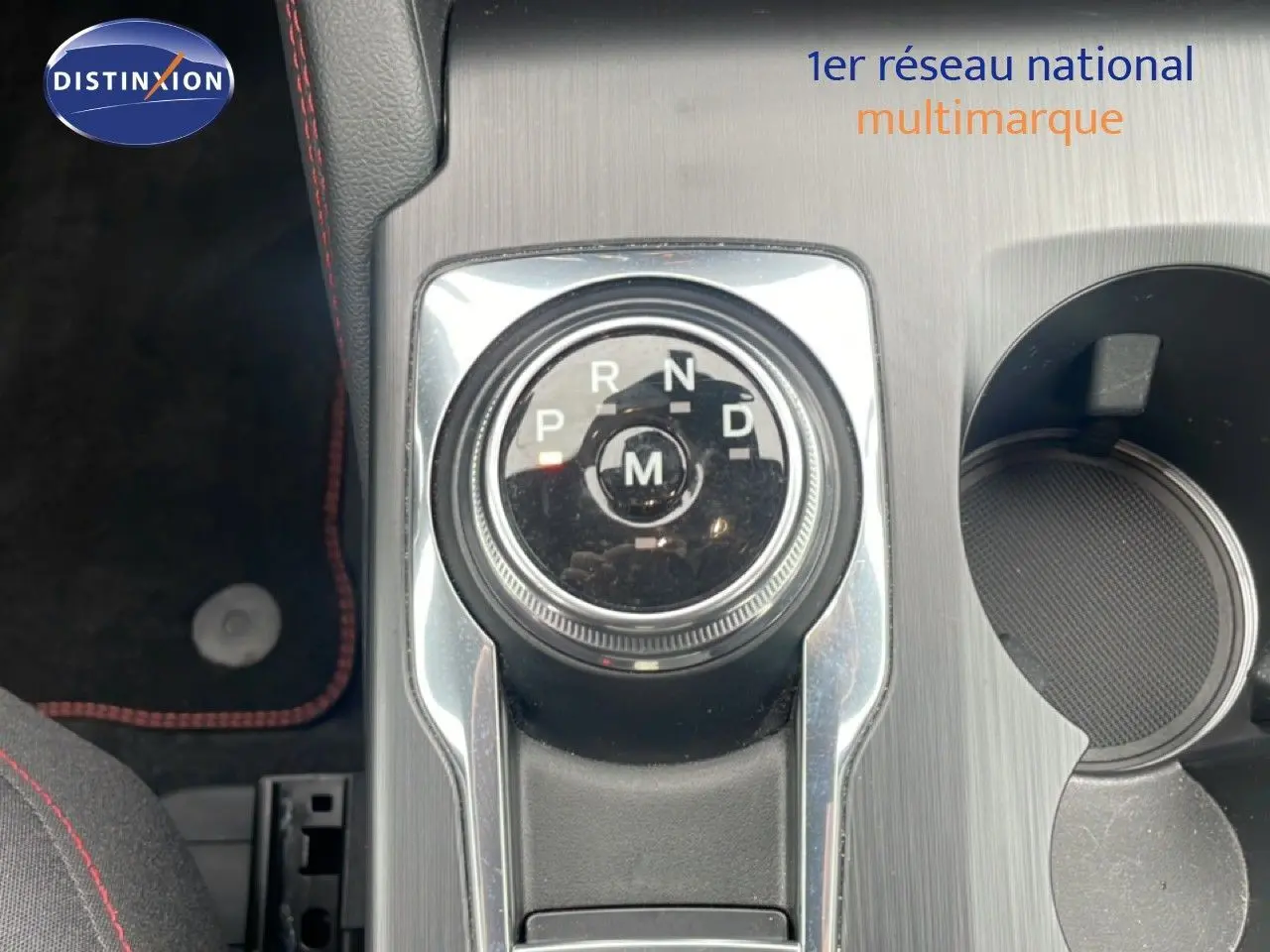 Gros plan sur la molette de boîte automatique du Ford Kuga bleu Vapor Metal, avec console grise et porte-gobelet visible.
