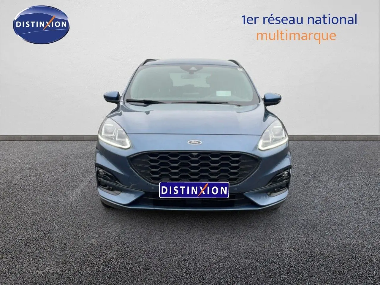 Vue frontale du Ford Kuga 2024 bleu Vapor Metal avec calandre noire et phares LED allumés.
