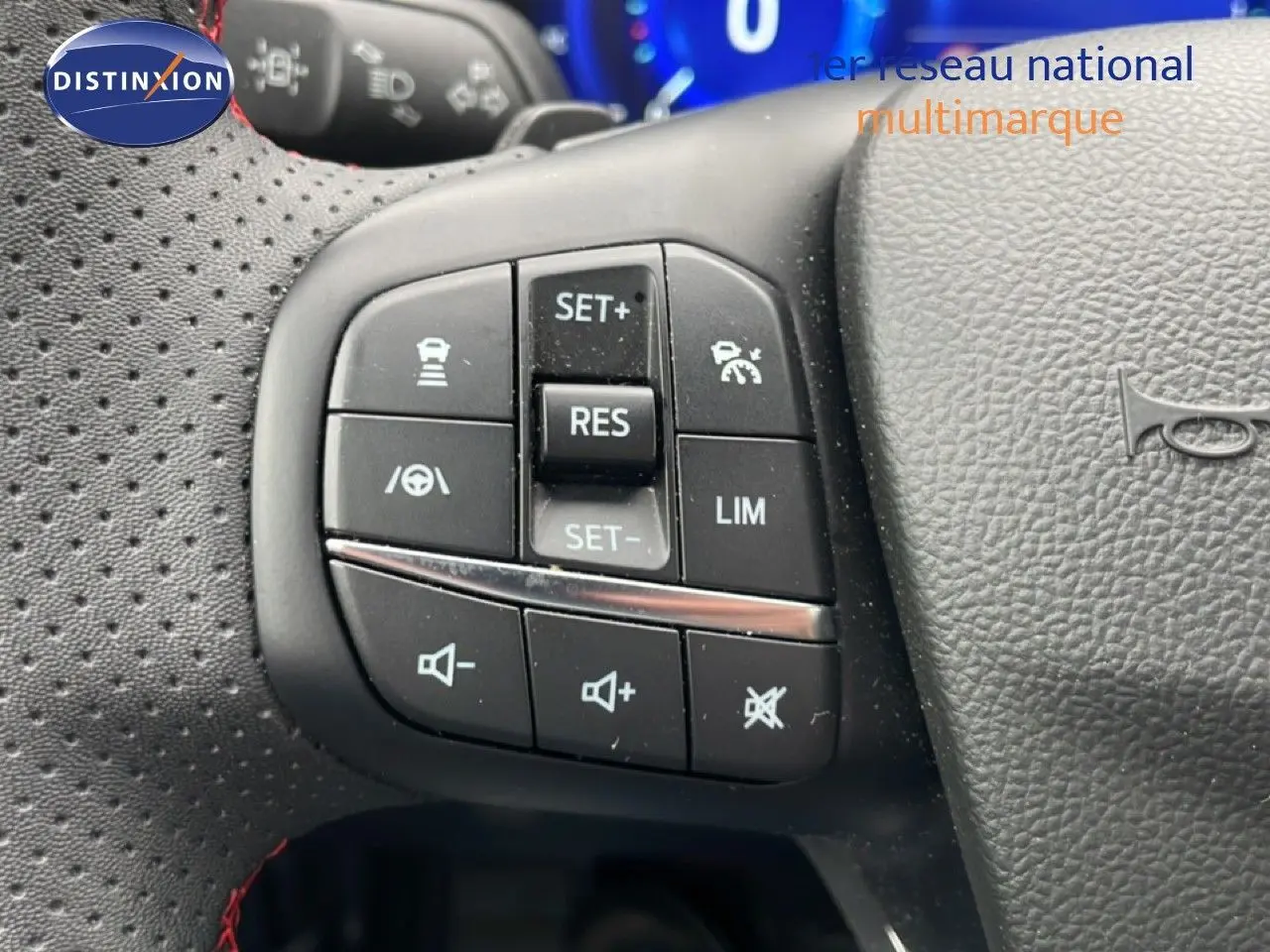 Gros plan sur les commandes de régulateur et volume au volant perforé noir du Ford Kuga bleu Vapor Metal 2024.