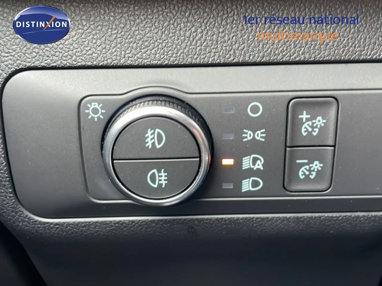 Gros plan sur le bouton de commande des feux d’un Ford Kuga 2024 bleu vapor metal, avec réglage des phares activé.