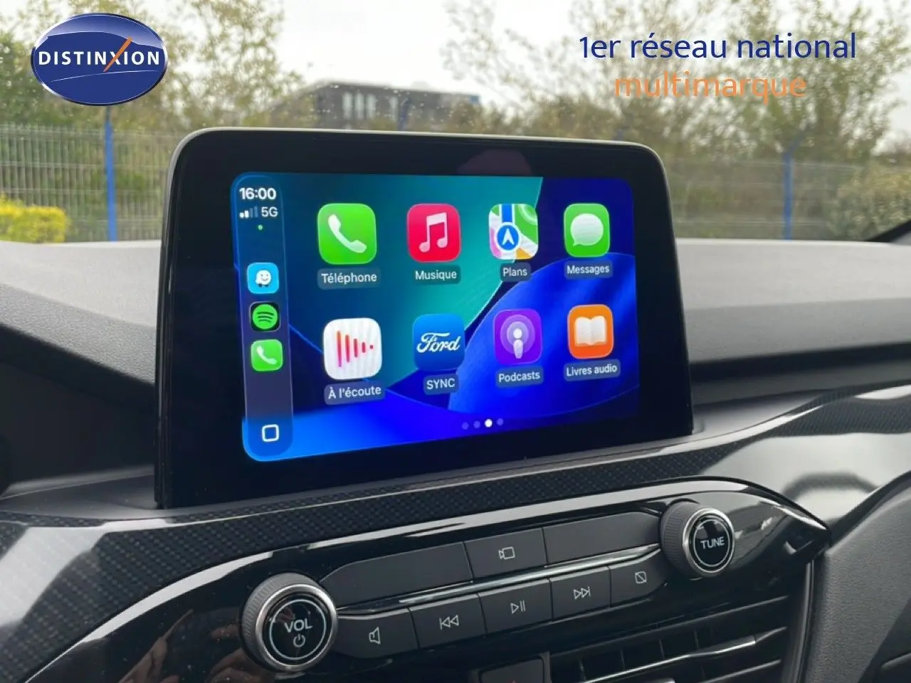 Écran tactile central du Ford Kuga 2024 affichant les applications connectées, avec tableau de bord en finition carbone.