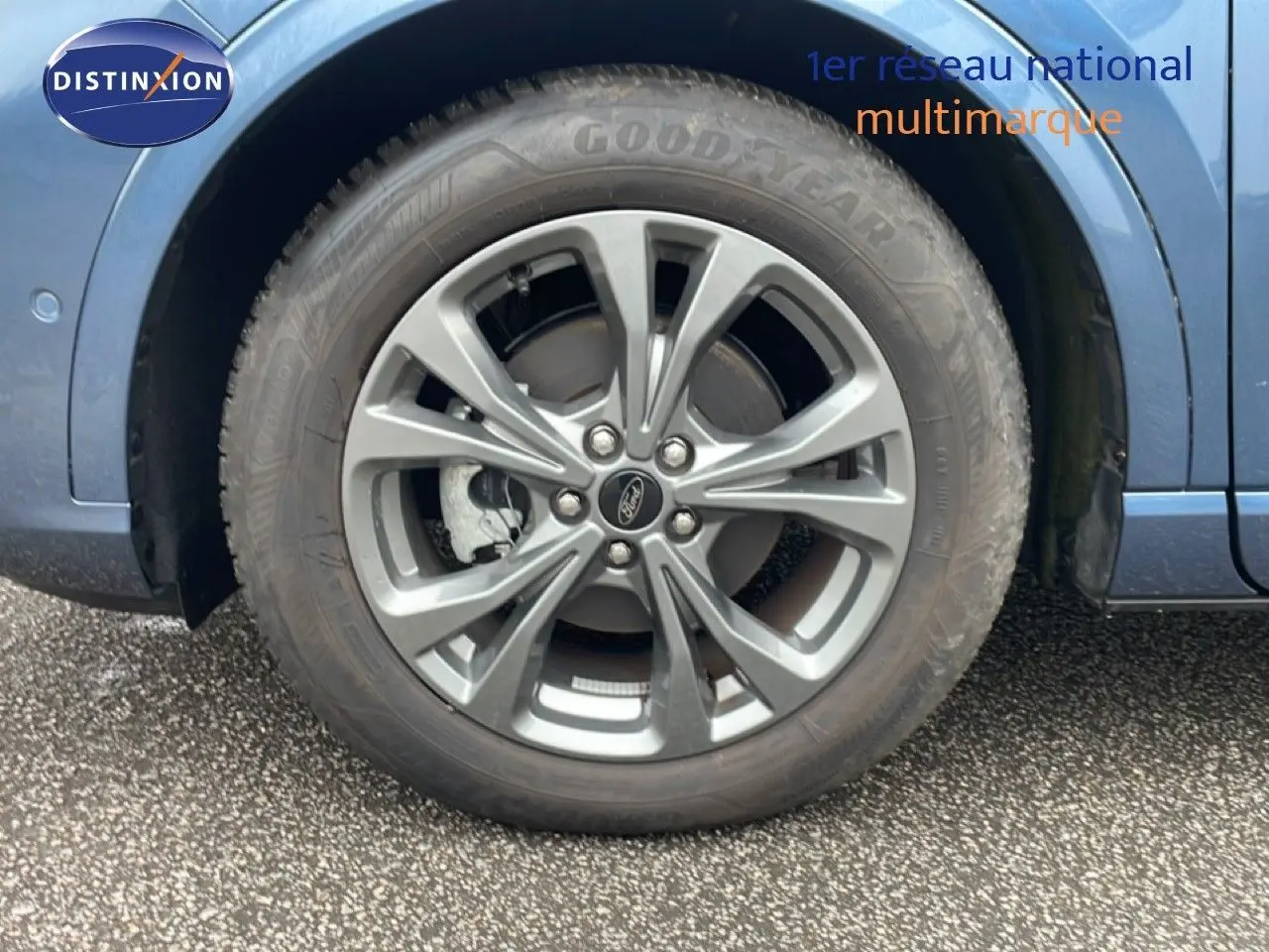 Gros plan sur la roue avant droite du Ford Kuga bleu vapor metal, mettant en valeur la jante alliage et le pneu Goodyear.