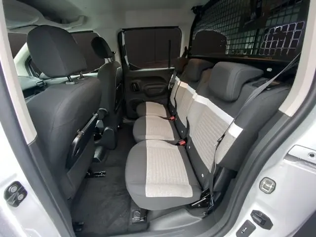 Vue intérieure côté droit du Citroën Berlingo blanc 2025, montrant la banquette arrière trois places avec sièges bicolores.