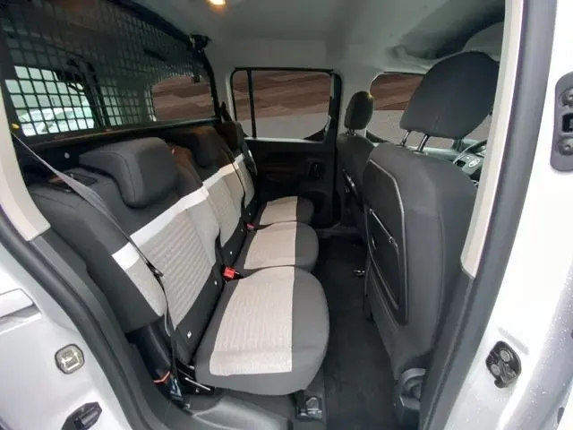 Vue intérieure arrière droite du Citroën Berlingo blanc 2025, montrant la banquette 3 places avec sièges bicolores gris clair et foncé.