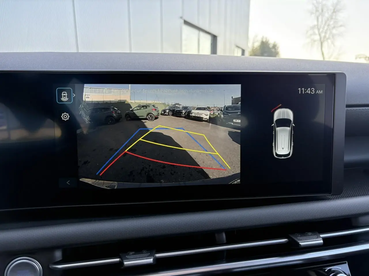 Vue intérieure du tableau de bord du Hyundai Tucson 2025 avec écran affichant la caméra de recul et l’aide au stationnement active.