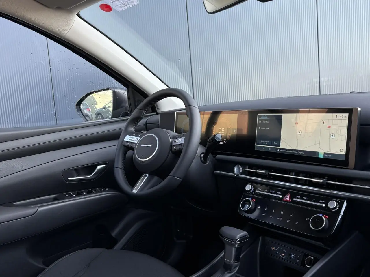 Intérieur du Hyundai Tucson 2025 vu côté conducteur, tableau de bord noir avec écran tactile large et volant cuir.