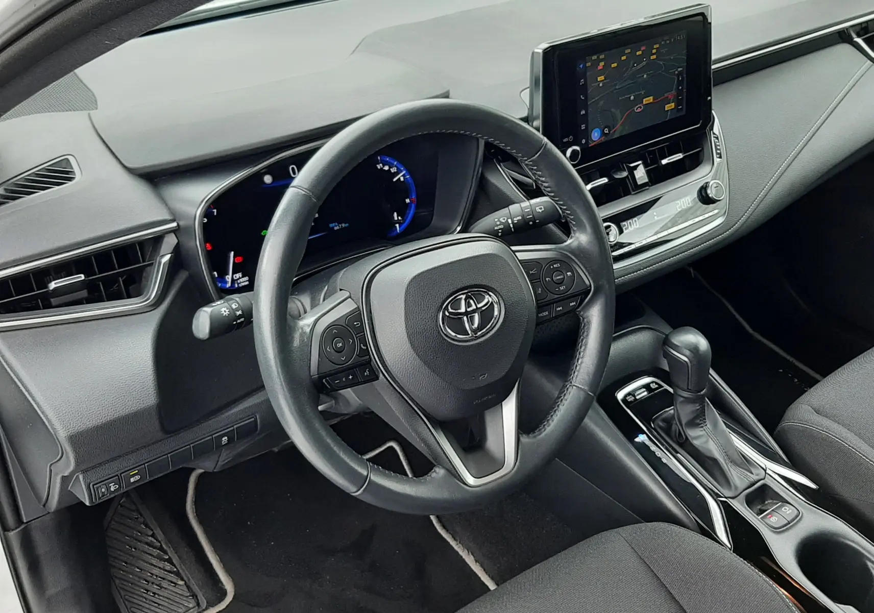 Vue intérieure côté conducteur de la Toyota Corolla 122 CH Dynamic 2022 blanche, tableau de bord et écran tactile visibles.