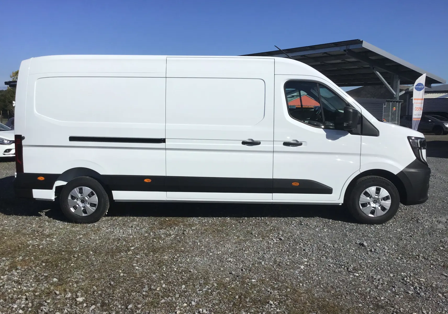 Vue latérale droite d'un utilitaire Renault Master blanc L3H2 2025 avec bandeaux noirs et jantes argentées.