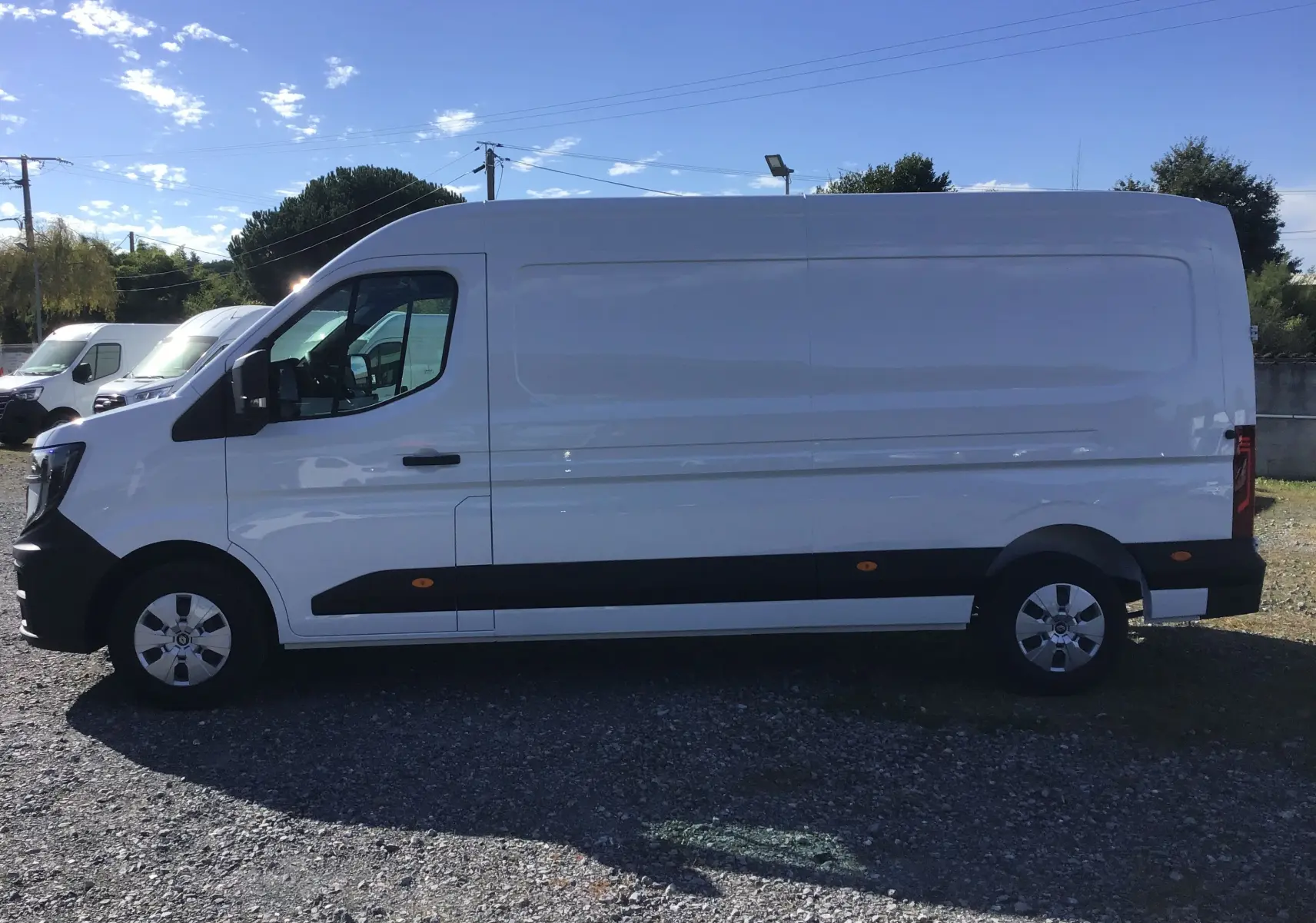 Vue de profil côté gauche d’un utilitaire Renault Master blanc L3H2 avec bandeau noir et jantes argentées.