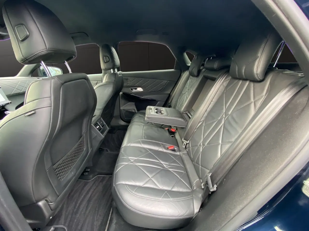 Vue intérieure côté droit des sièges arrière en cuir noir matelassé du DS7 2024, avec accoudoir central déployé.