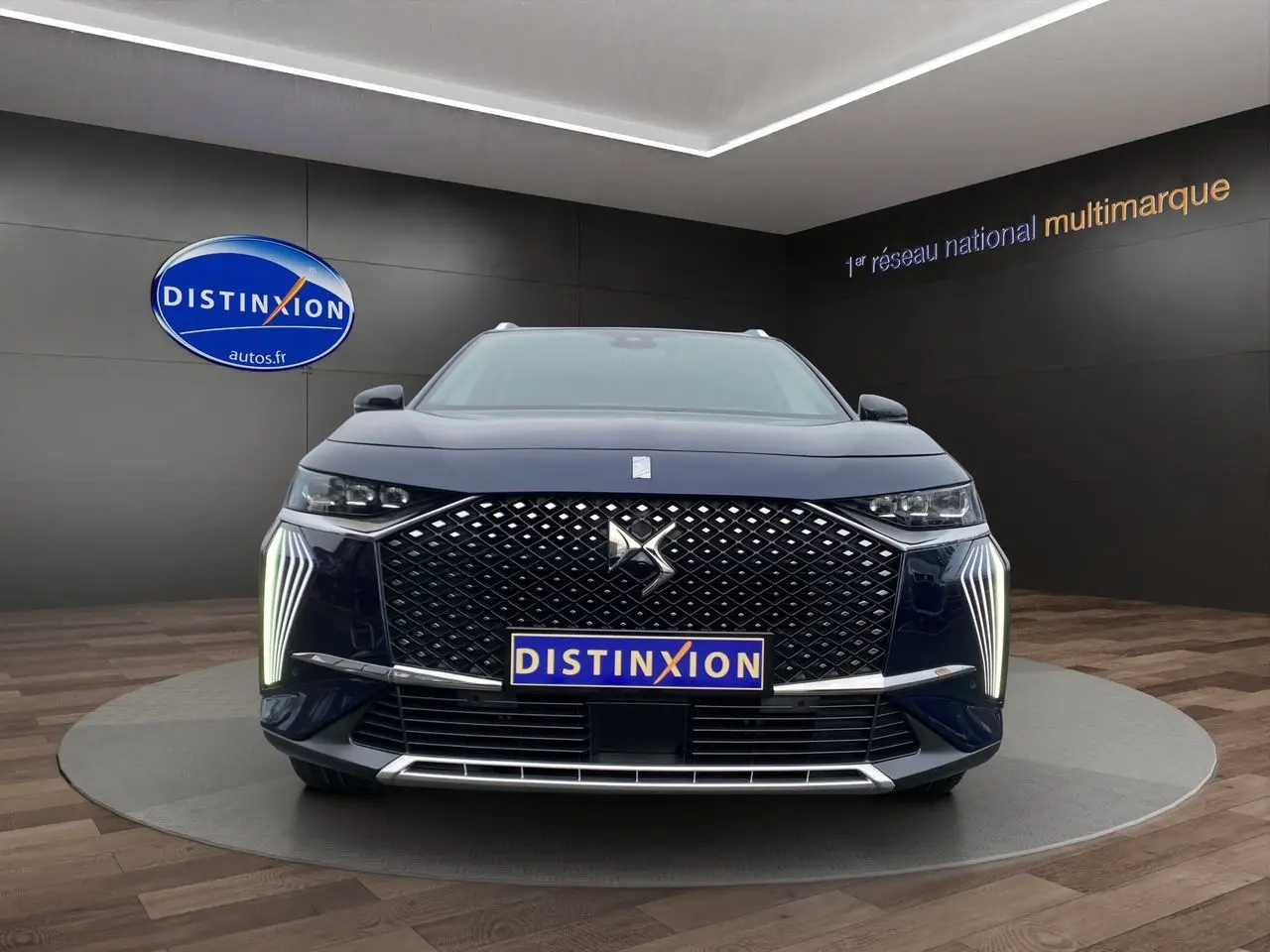 Vue frontale d'un DS7 Bleu Éclipse 2024 avec calandre distinctive et feux LED verticaux allumés.