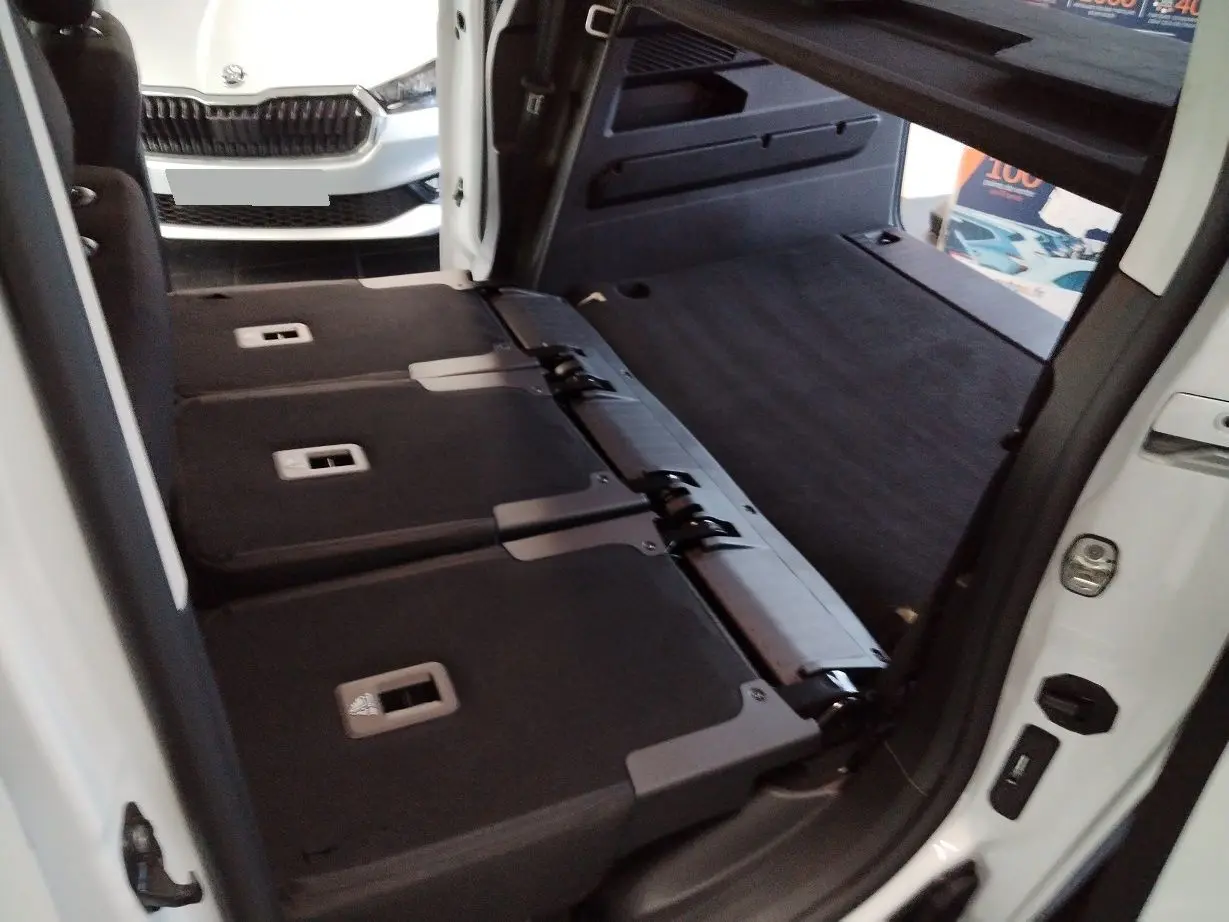 Vue intérieure arrière du Citroën Berlingo blanc 2025, sièges arrière rabattus et coffre spacieux visible.