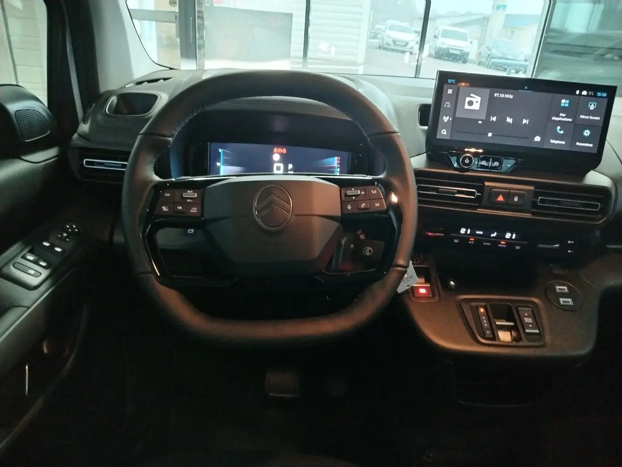 Vue intérieure centrée sur le volant et le tableau de bord numérique du Citroën Berlingo 2025 avec écran tactile et commandes intégrées.