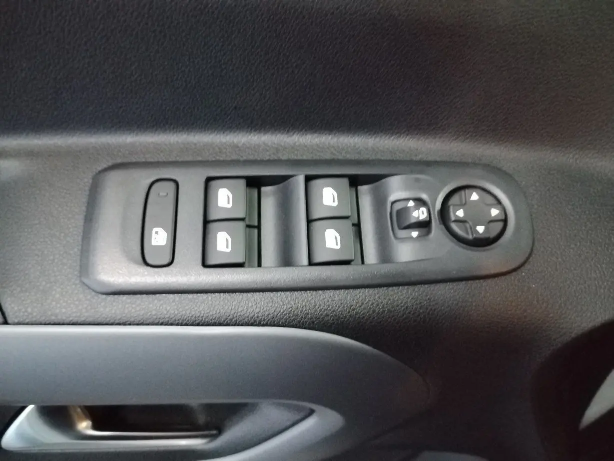 Gros plan sur les commandes de lève-vitres et réglage des rétroviseurs côté conducteur du Citroën Berlingo blanc 2025.