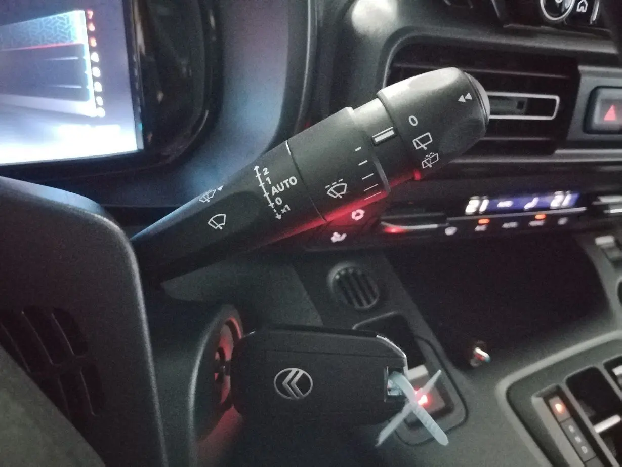 Gros plan sur la commande d’essuie-glace et clé de contact dans l’habitacle du Citroën Berlingo blanc 2025.