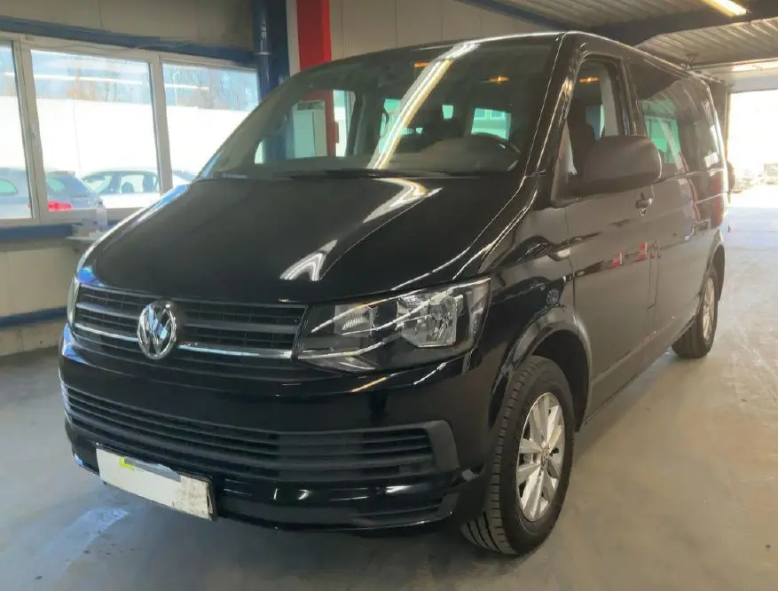 Volkswagen Multivan T6 noir vu en 3/4 avant droit dans un garage avec éclairage intérieur chaud.