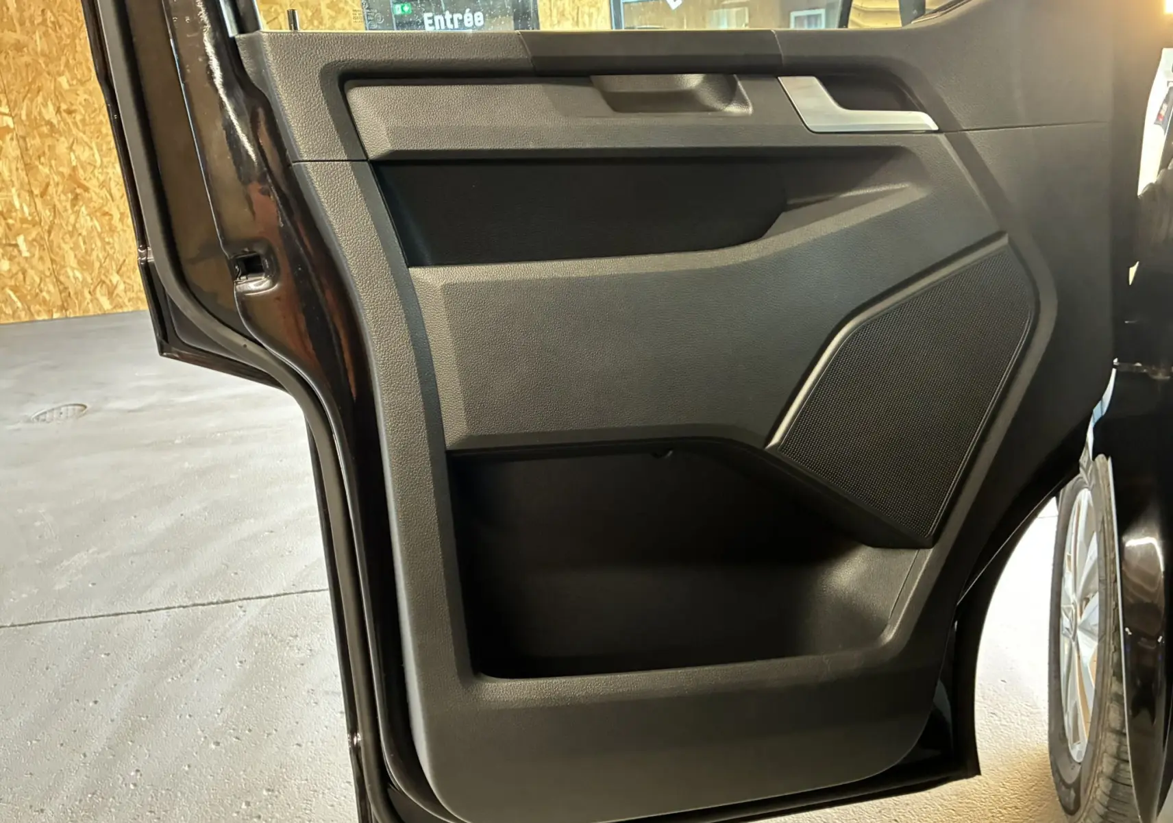 Vue rapprochée de la porte arrière gauche noire du Volkswagen Multivan T6 PH.1, avec haut-parleur intégré et rangement.