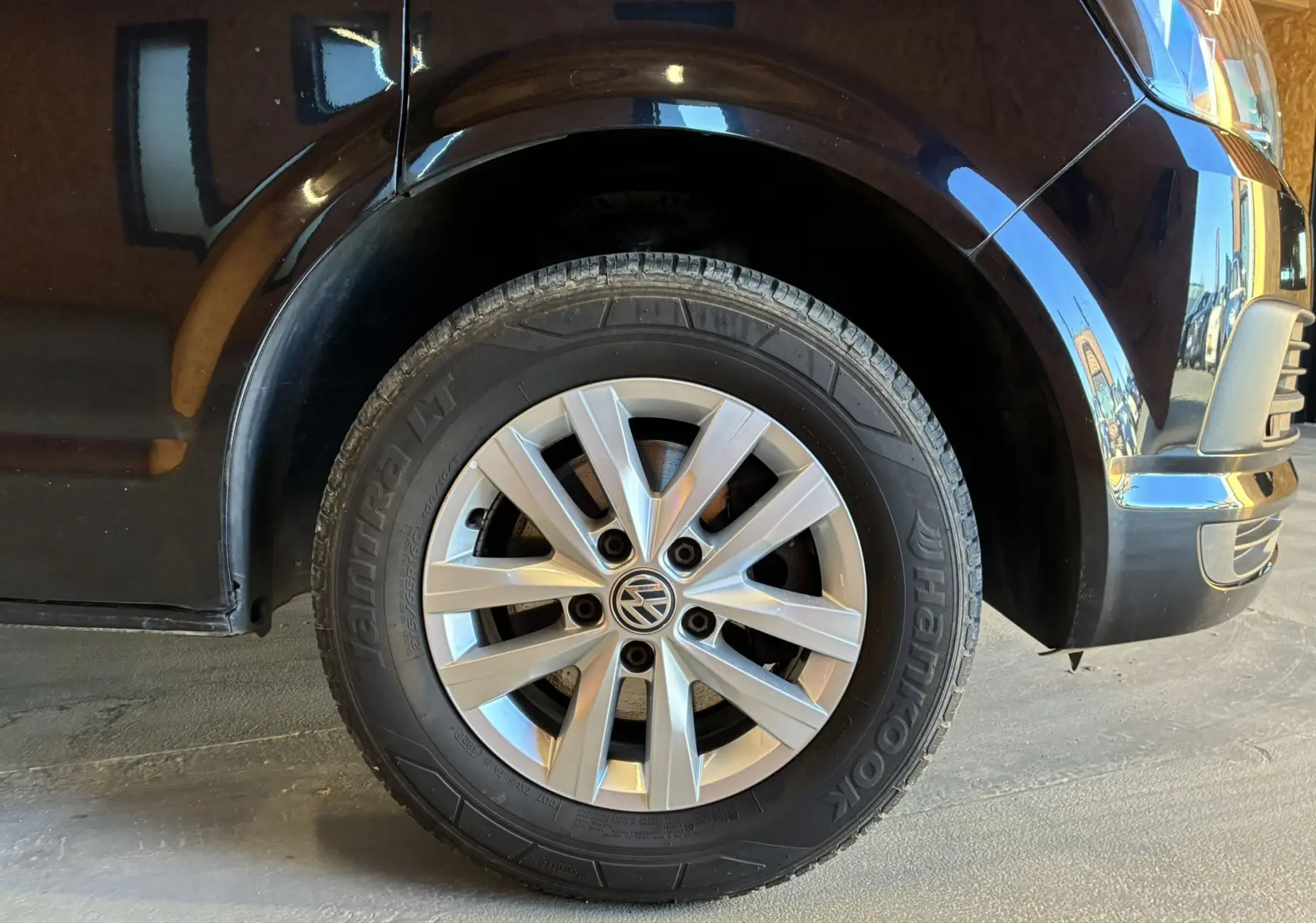 Gros plan sur la roue avant droite d’un Volkswagen Multivan noir T6 avec jante argentée et pneu Hankook.