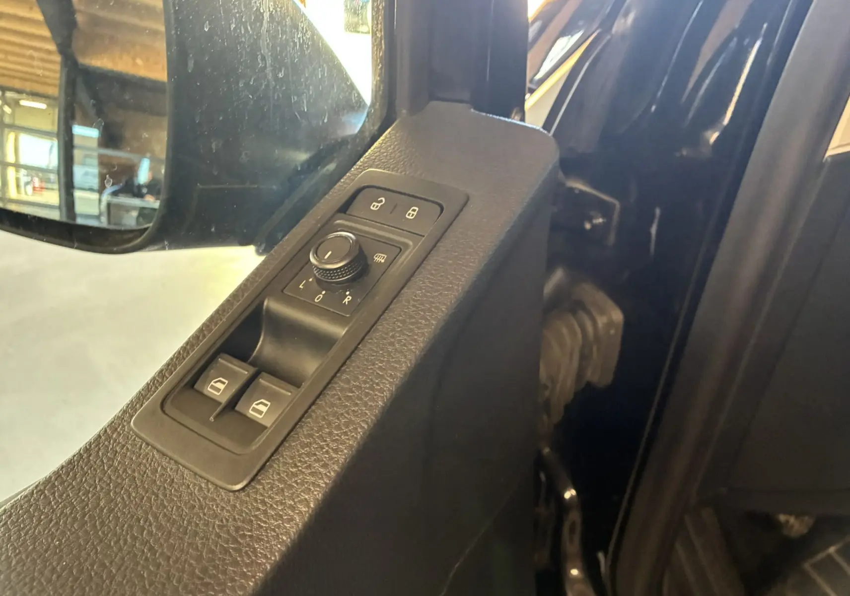 Vue rapprochée du panneau de commandes des rétroviseurs et vitres côté conducteur du Volkswagen Multivan noir T6 PH.1 2015.