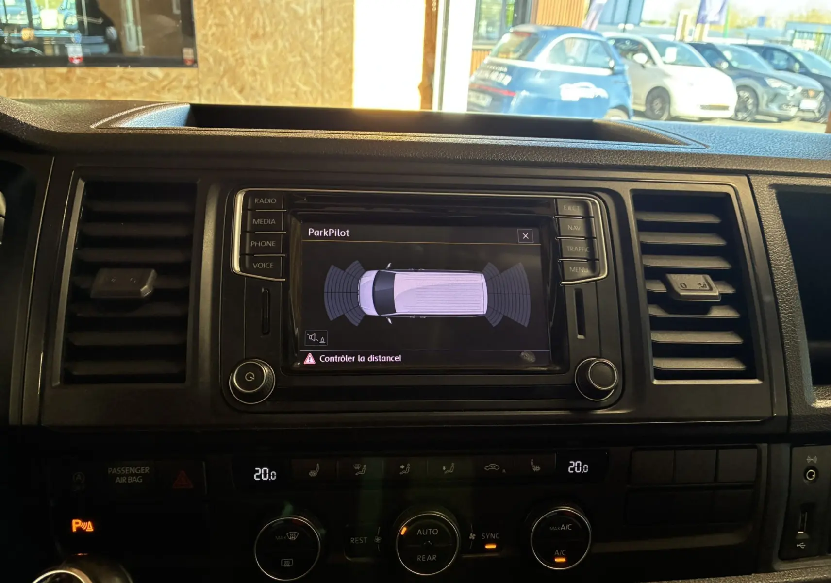 Vue intérieure du tableau de bord du Volkswagen Multivan T6 noir, affichant l'écran ParkPilot et les commandes de climatisation.