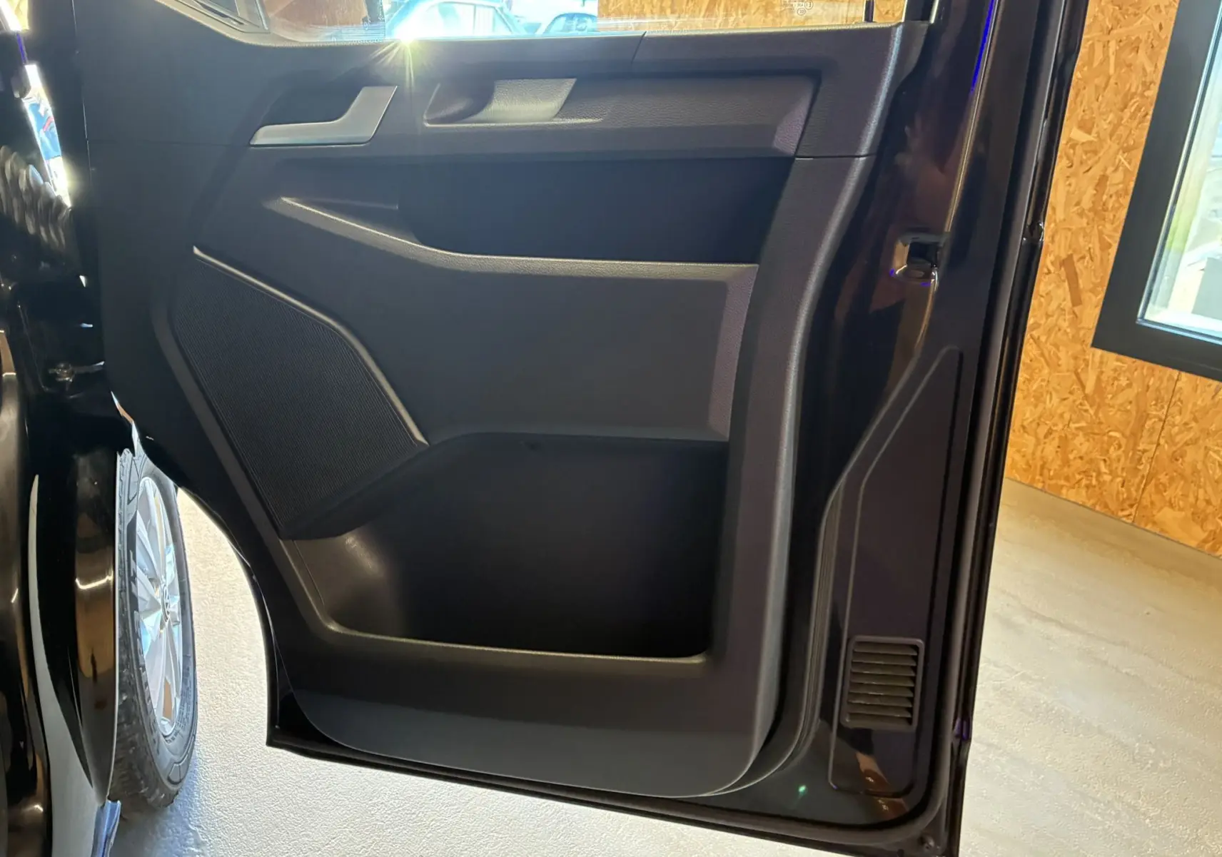 Vue rapprochée de la porte arrière droite noire du Volkswagen Multivan T6 PH.1, avec haut-parleur intégré et poignée visible.