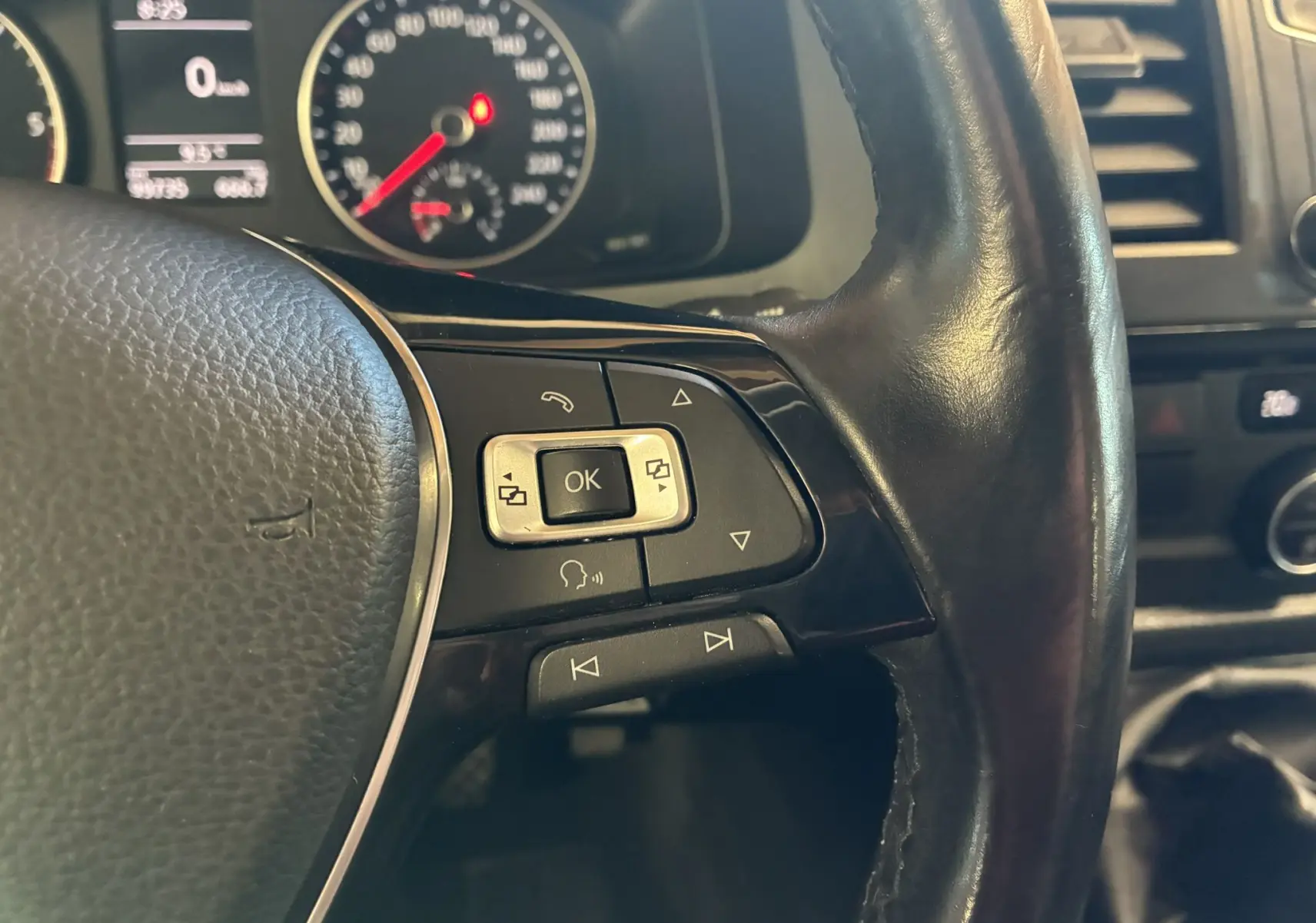 Gros plan sur le volant noir du Volkswagen Multivan T6 avec commandes intégrées et tableau de bord en arrière-plan.