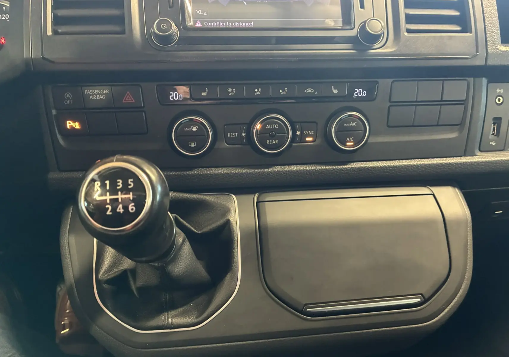 Vue rapprochée de la console centrale du Volkswagen Multivan T6 noir, mettant en valeur le levier de vitesses manuel et les commandes de climatisation.