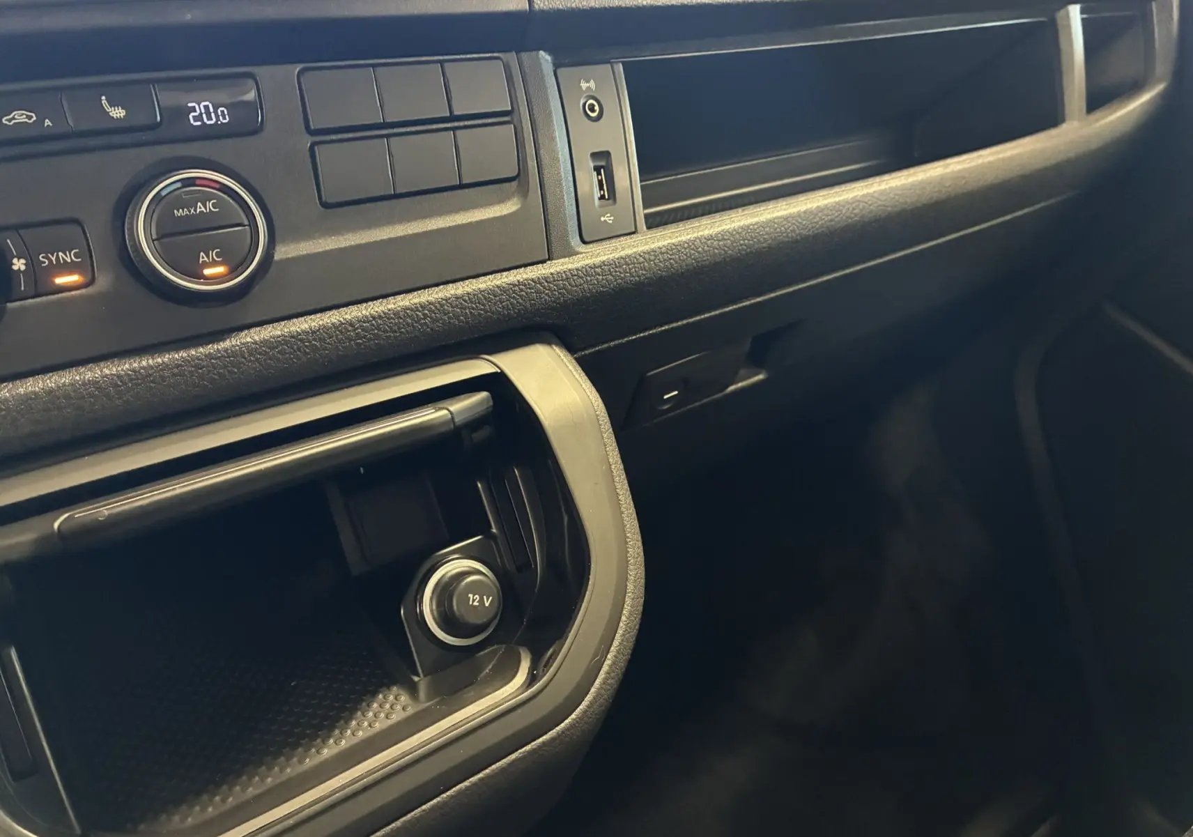 Vue rapprochée de la console centrale noire du Volkswagen Multivan T6 avec commandes climatisation et prise 12V visibles.