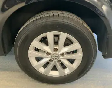 Volkswagen Multivan T6 noir vu en 3/4 arrière droit dans un garage avec vitres teintées et feux rouges.