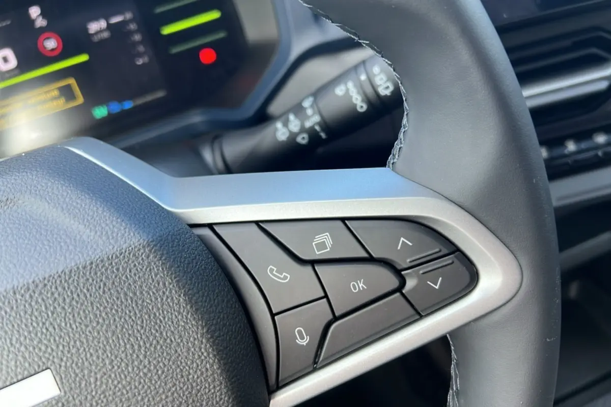 Gros plan sur le volant cuir à commandes multifonctions du Dacia Bigster Hybrid 155 Expression Plus, intérieur moderne.