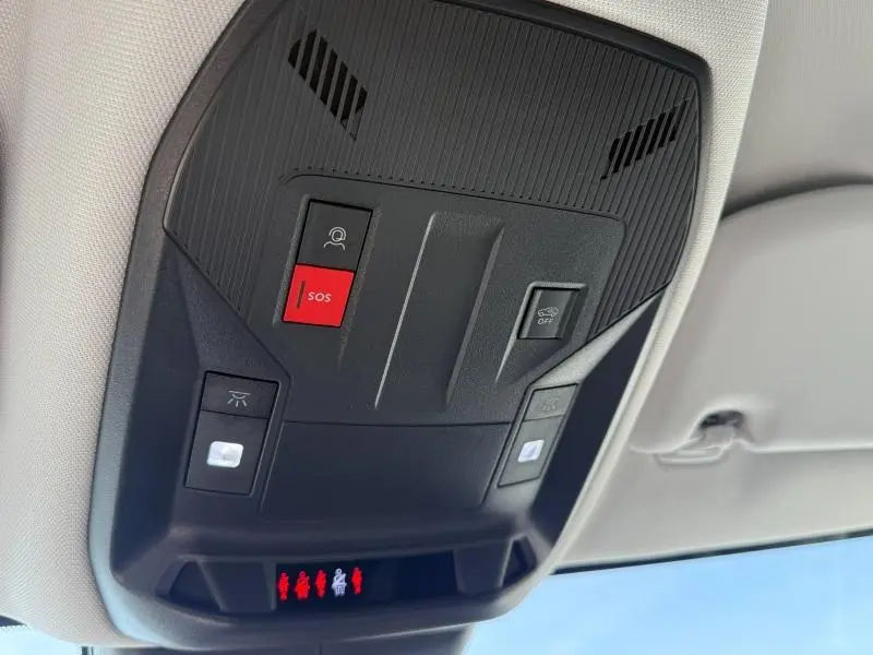 Vue en contre-plongée du plafonnier noir avec bouton SOS rouge et éclairages intérieurs d'une Peugeot 308 blanche 2025 hybride.