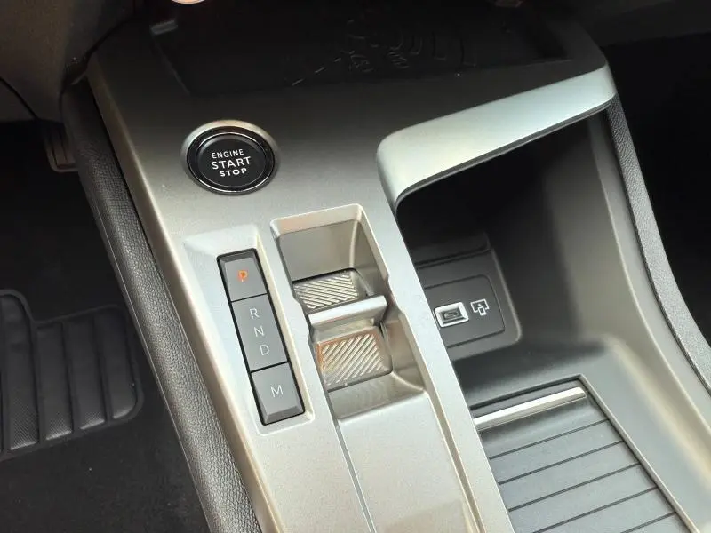 Gros plan sur la console centrale argentée du Peugeot 308 Hybrid 2025 avec bouton start/stop et commandes de boîte automatique.