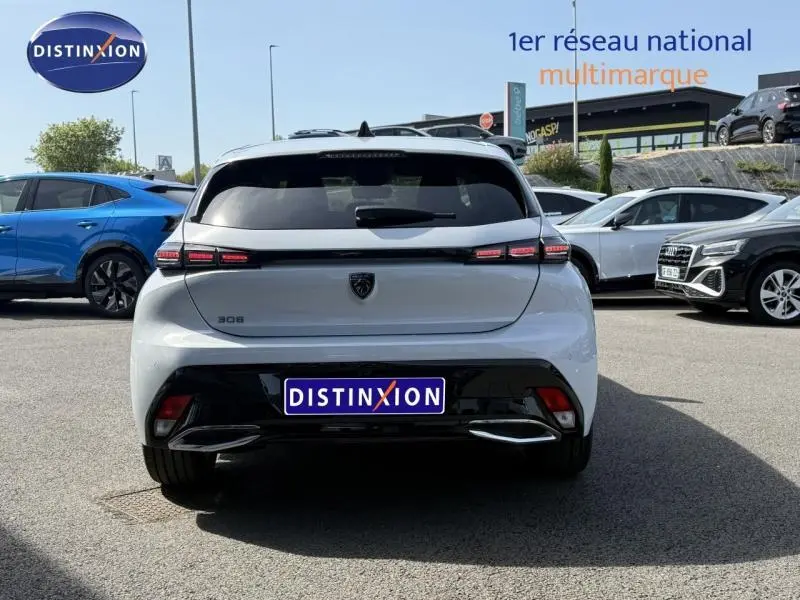 Vue arrière d'une Peugeot 308 blanche Okénite 2025 avec feux LED distinctifs et logo noir au centre du hayon.