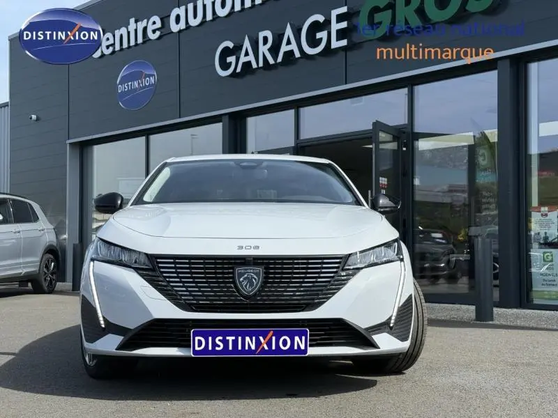 Vue frontale d'une Peugeot 308 1.2 Hybrid blanche Okénite avec calandre noire et logo lion distinctif.