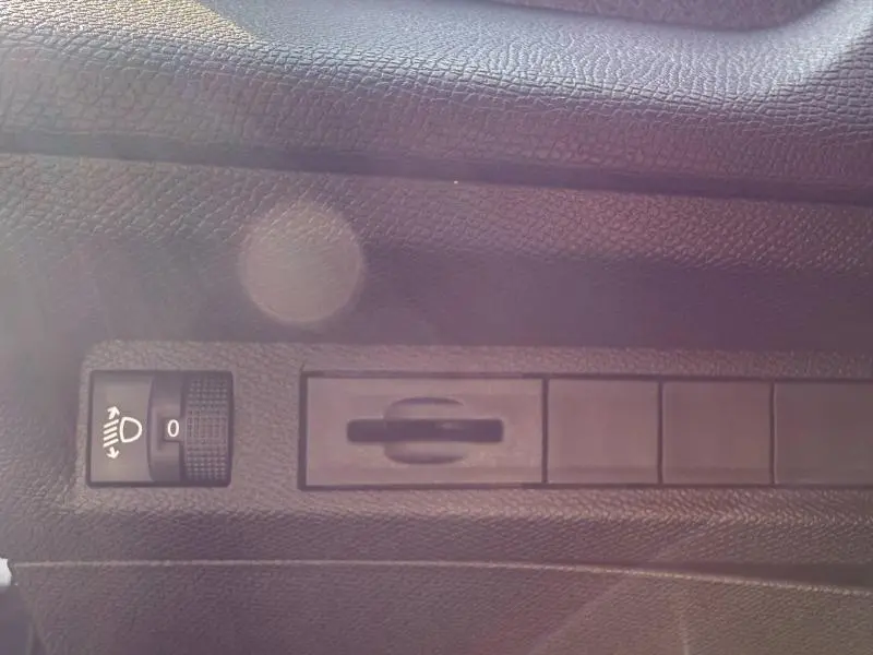 Détail intérieur du tableau de bord du Peugeot 308 2025, montrant la molette de réglage des phares sur fond noir texturé.