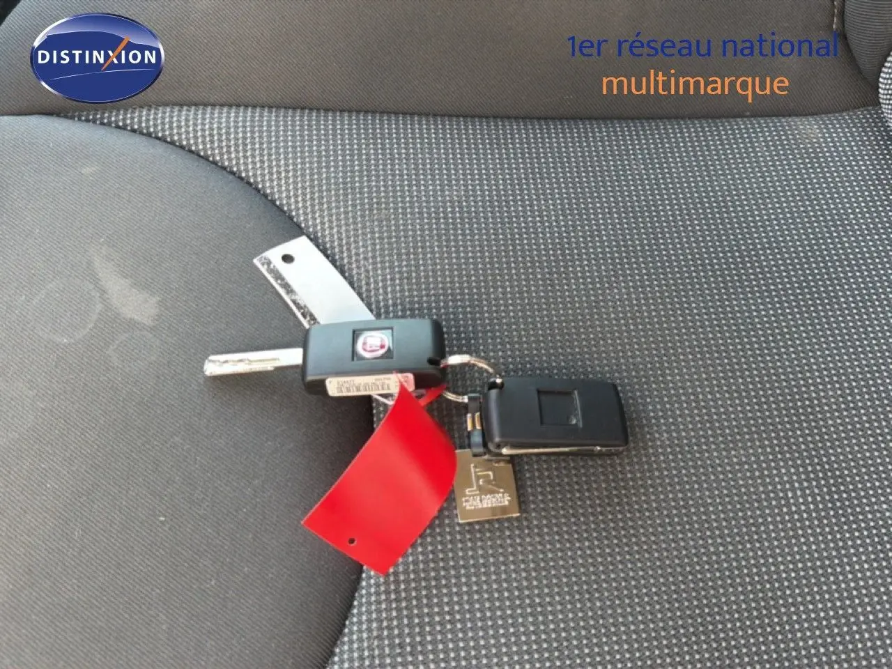 Clé de FIAT Scudo Fourgon gris métal 2016 posée sur un siège tissu gris à motifs fins.