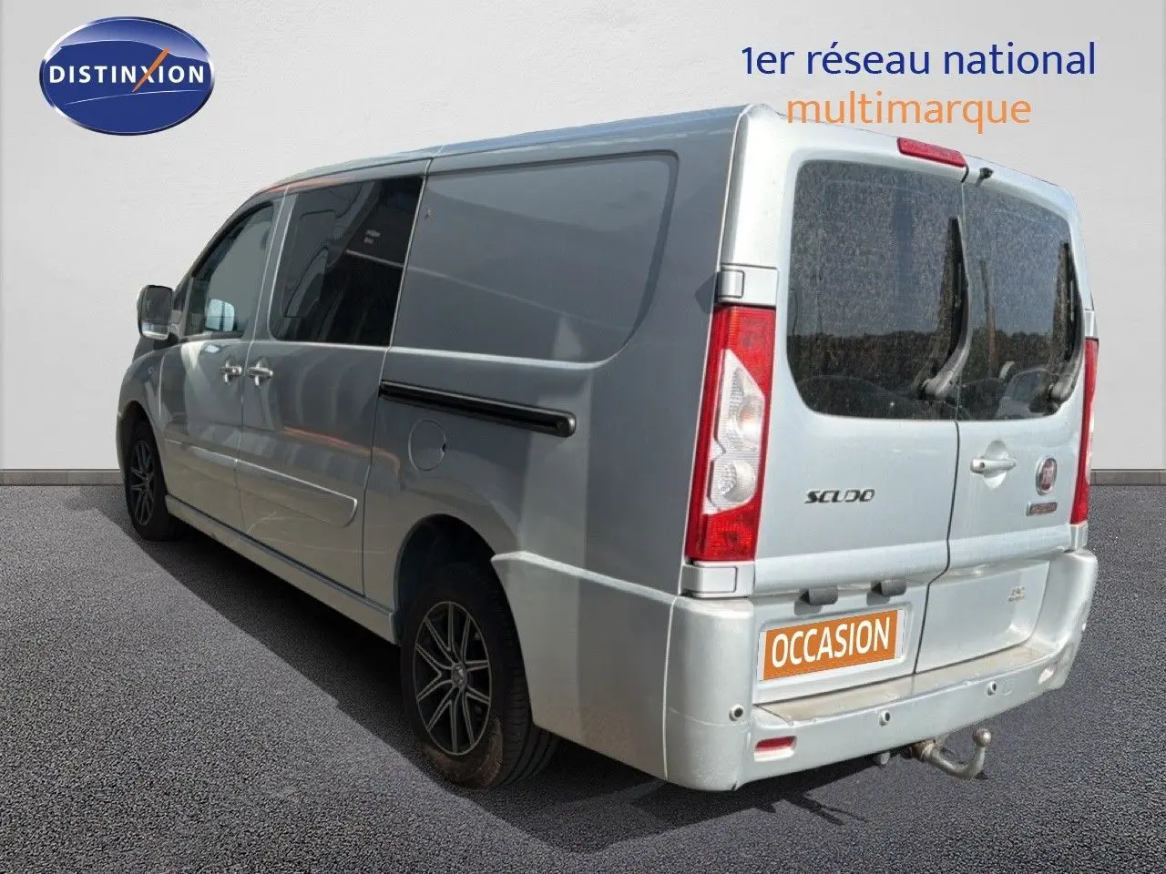 Vue 3/4 arrière droite d’un FIAT Scudo Fourgon gris métal avec hayon arrière vitré et attelage visible.
