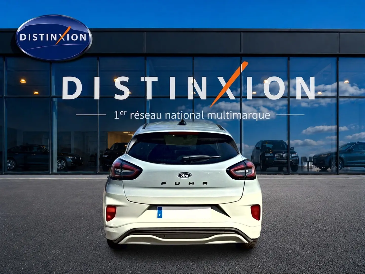 Vue arrière d'un Ford Puma gris cactus garé devant une vitrine avec logo Distinxion.