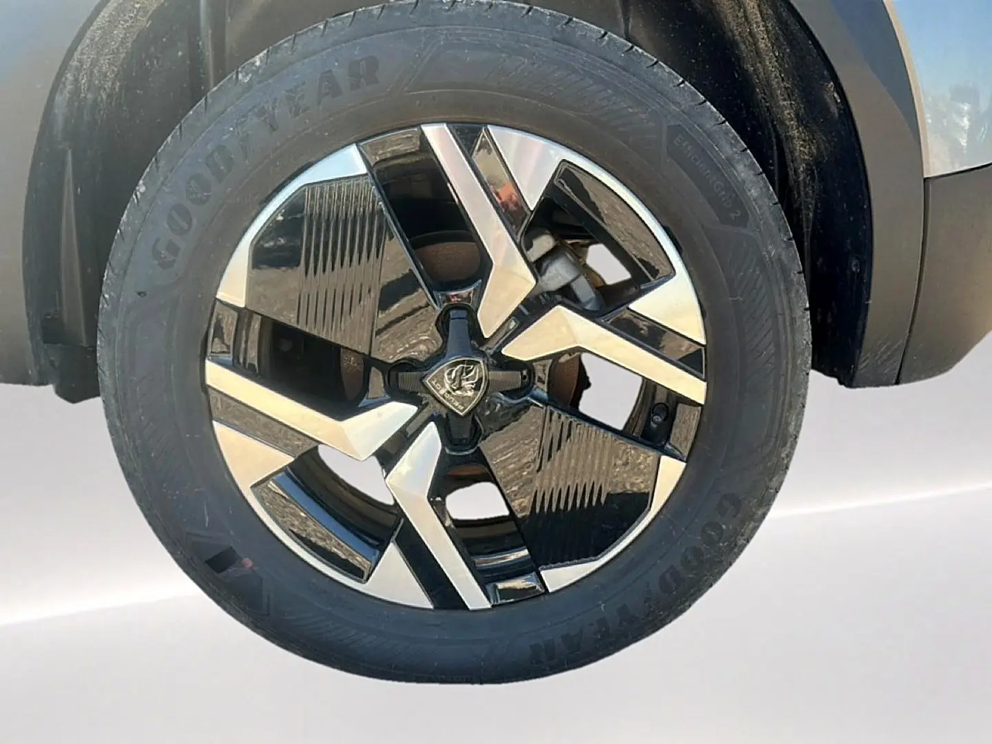 Gros plan sur la jante alu bicolore noire et argentée du côté avant droit du Peugeot 2008 gris Artense.