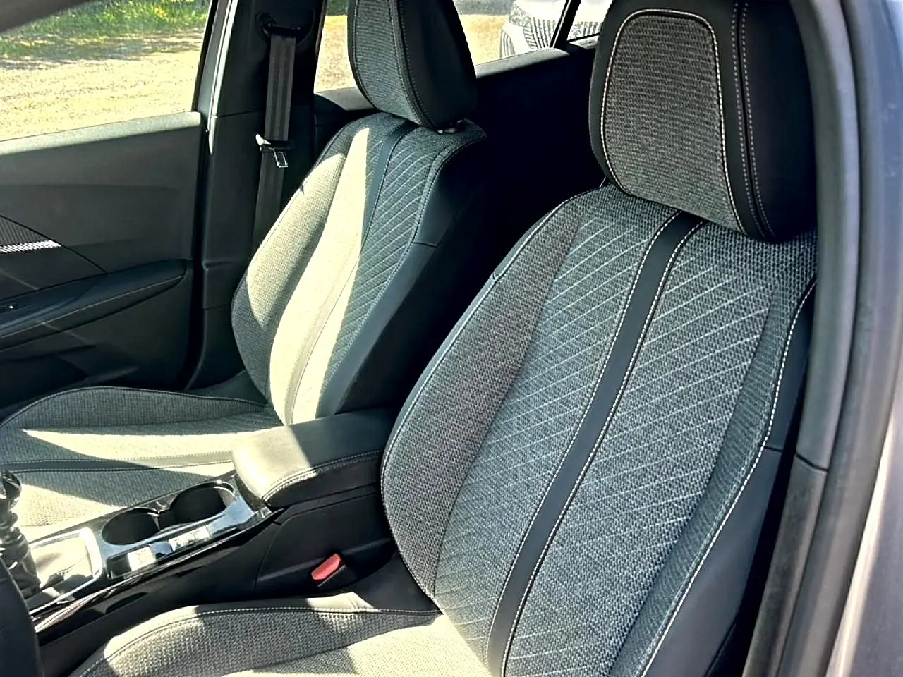Vue intérieure rapprochée des sièges avant en tissu gris embossé de la Peugeot 2008 1.2 100 Allure 2025.