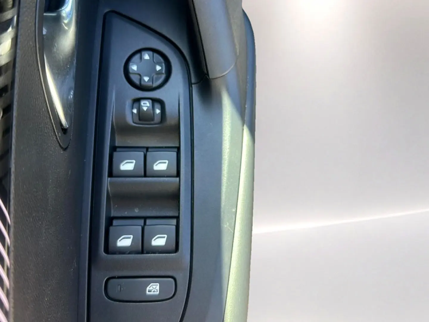 Détail des commandes des vitres et rétroviseurs côté conducteur de la Peugeot 2008 gris Artense, intérieur noir.