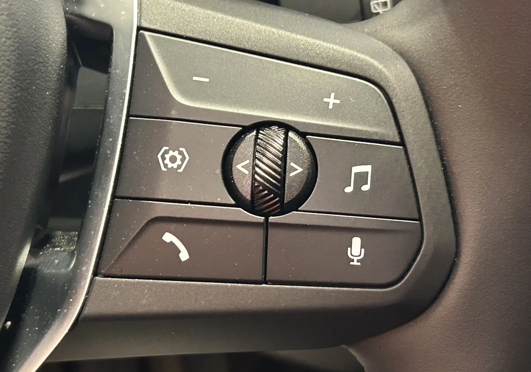 Gros plan sur les commandes audio et téléphone au volant d'une BMW Série 1 120DA gris Skyscrap de 2024.