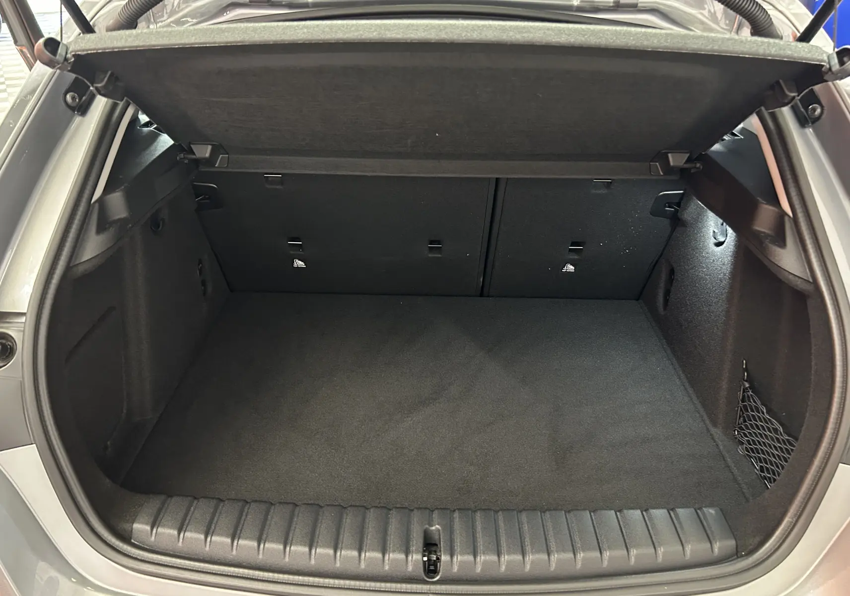 Coffre ouvert vu de l'arrière d'une BMW Série 1 gris Skyscrap, espace de chargement propre et vide.