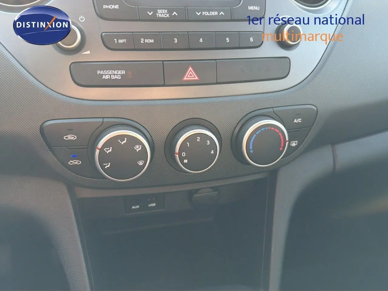 Gros plan sur la console centrale de la Hyundai i10 blanche 2018, montrant les commandes de climatisation et la radio.