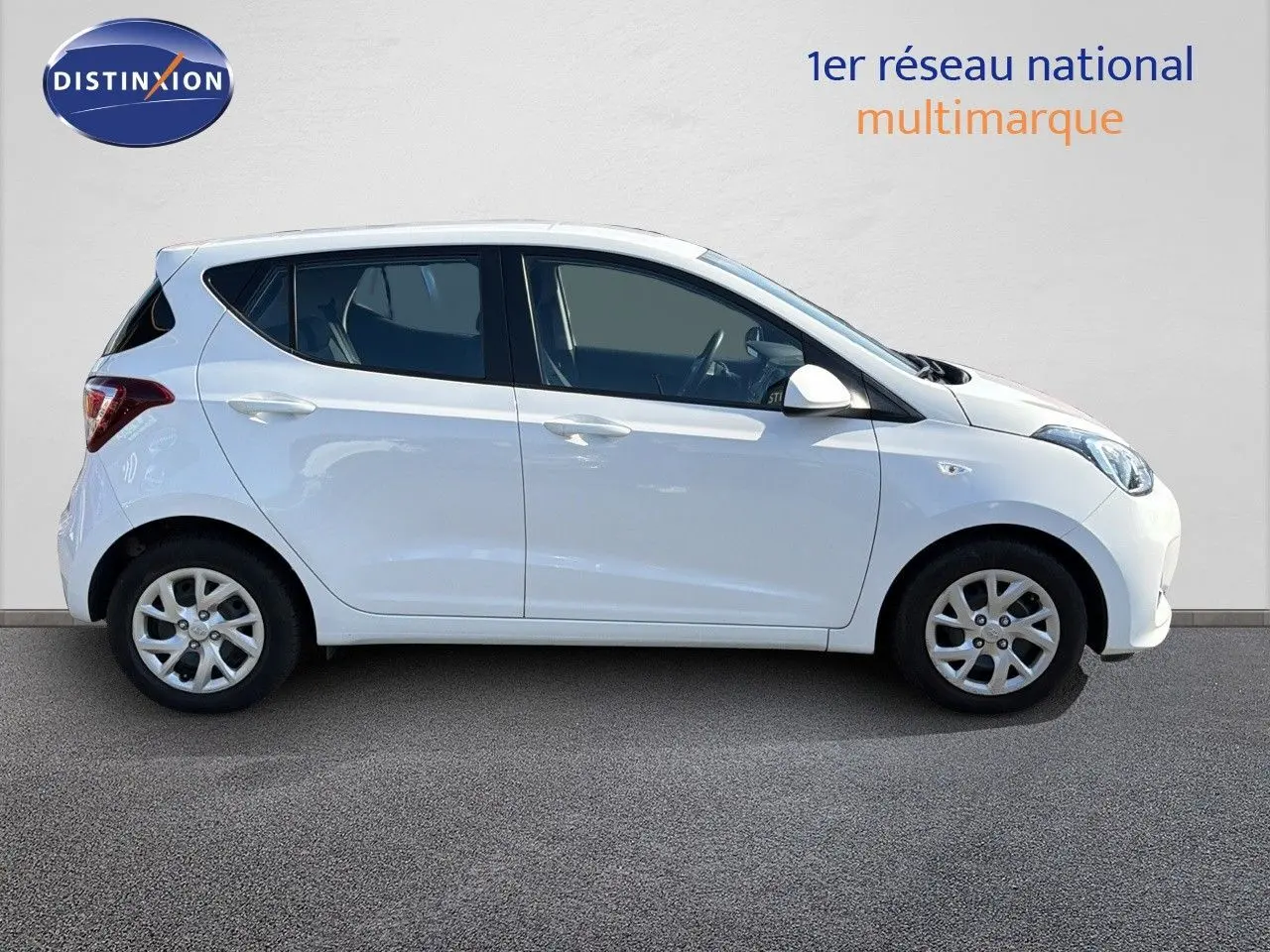Profil latéral droit d'une Hyundai i10 blanche de 2018, compacte et cinq portes, sur fond neutre.