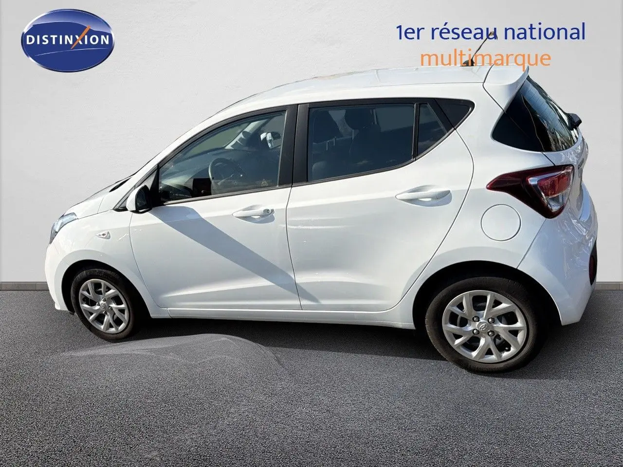 Profil côté gauche d'une Hyundai i10 blanche 2018, compacte cinq portes avec jantes alliage et vitres teintées.